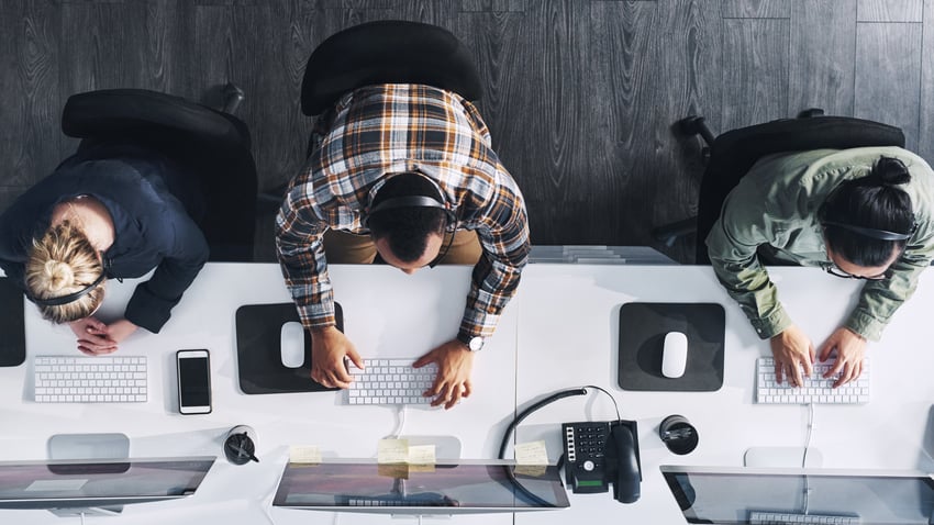 Draufsicht einer Gruppe von Kontakt-Center-Agenten, die in einem Büro arbeiten